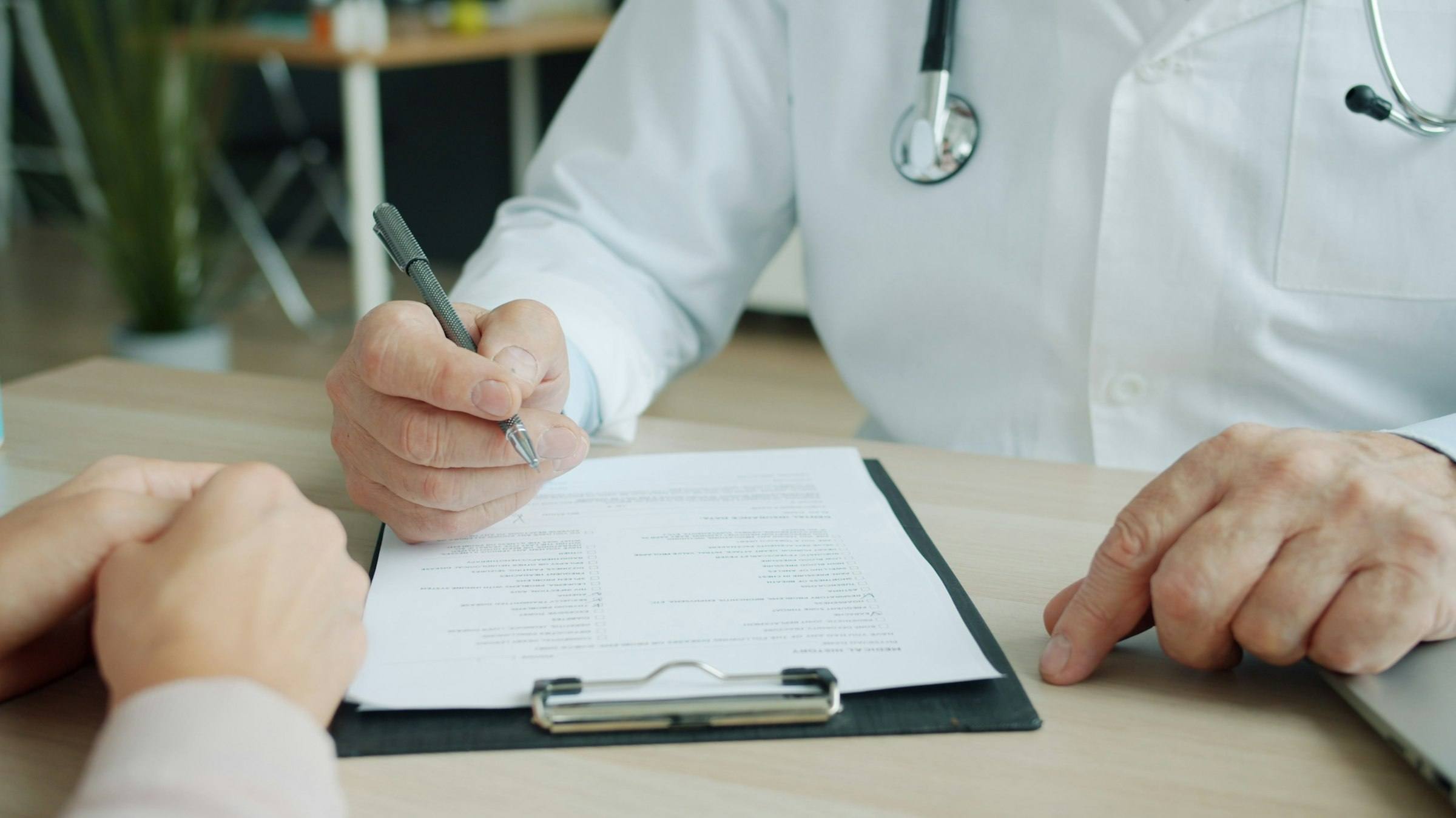 A doctor filling in a patient chart on a clipboard
